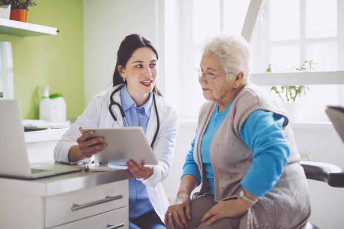 doctor showing clipboard to an elderly patient
