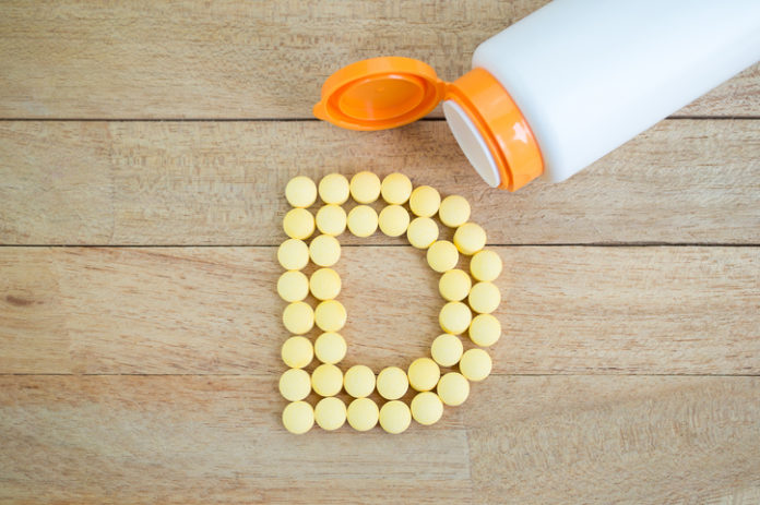 Yellow pills forming shape to D alphabet on wood background