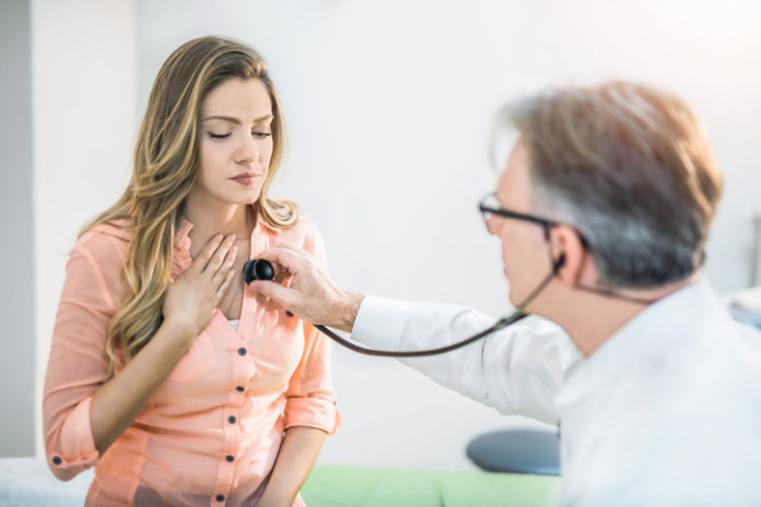 Young woman getting her painful chest examined by a doctor.